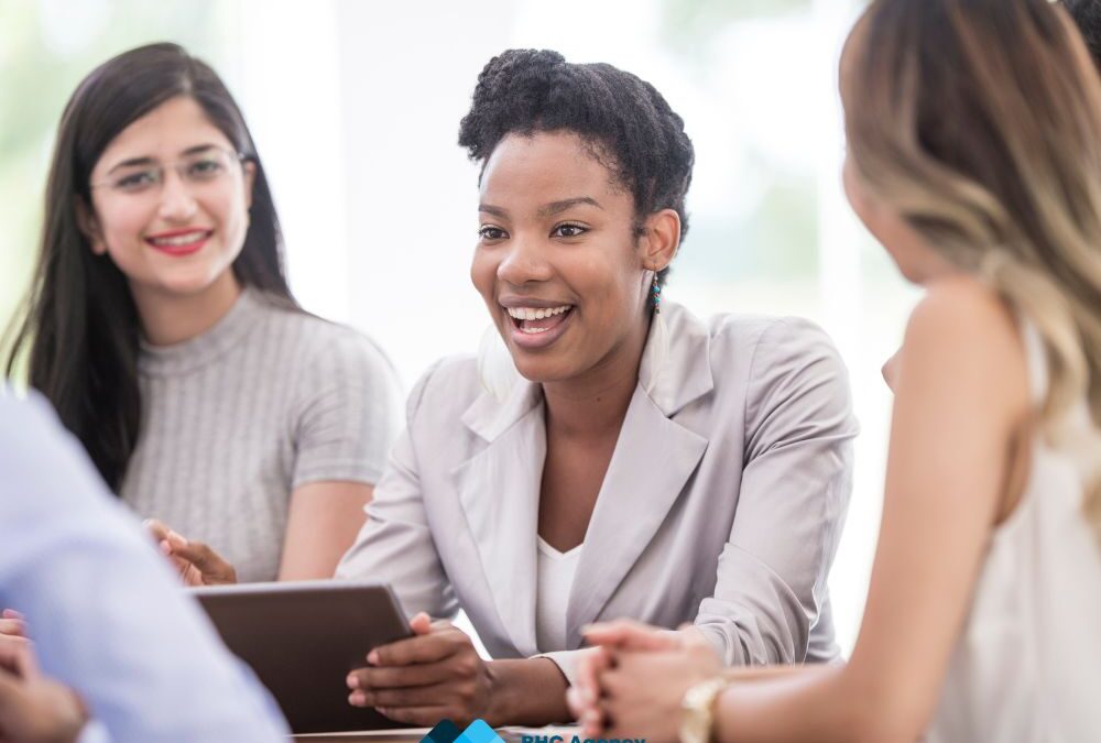 3 female professional coworkers sitting together smile and talk